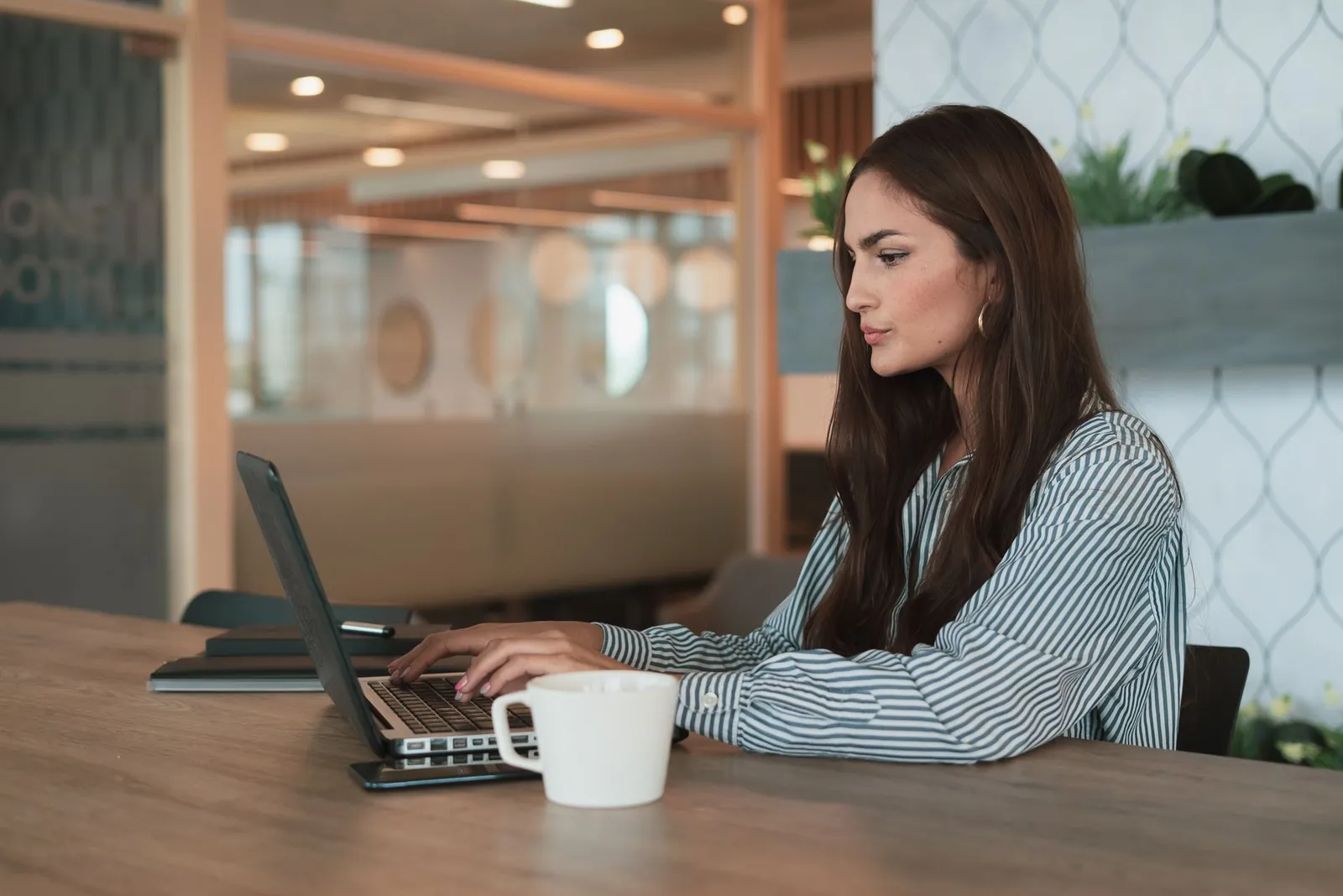 Servidora trabalhando no notebook em um escritório claro e moderno